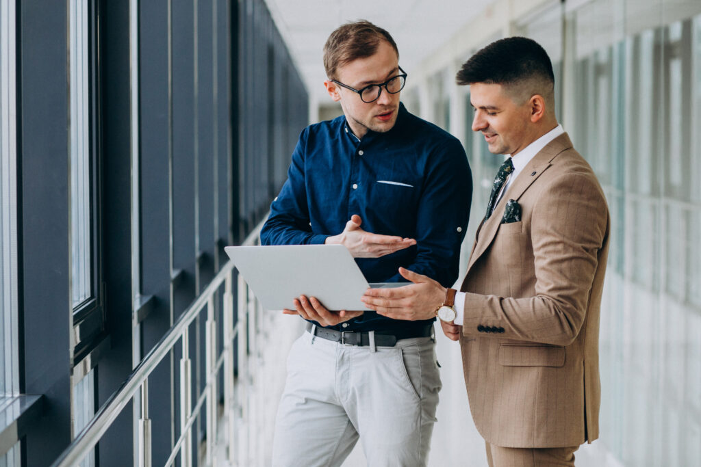 two male colleagues office standing with laptop scaled